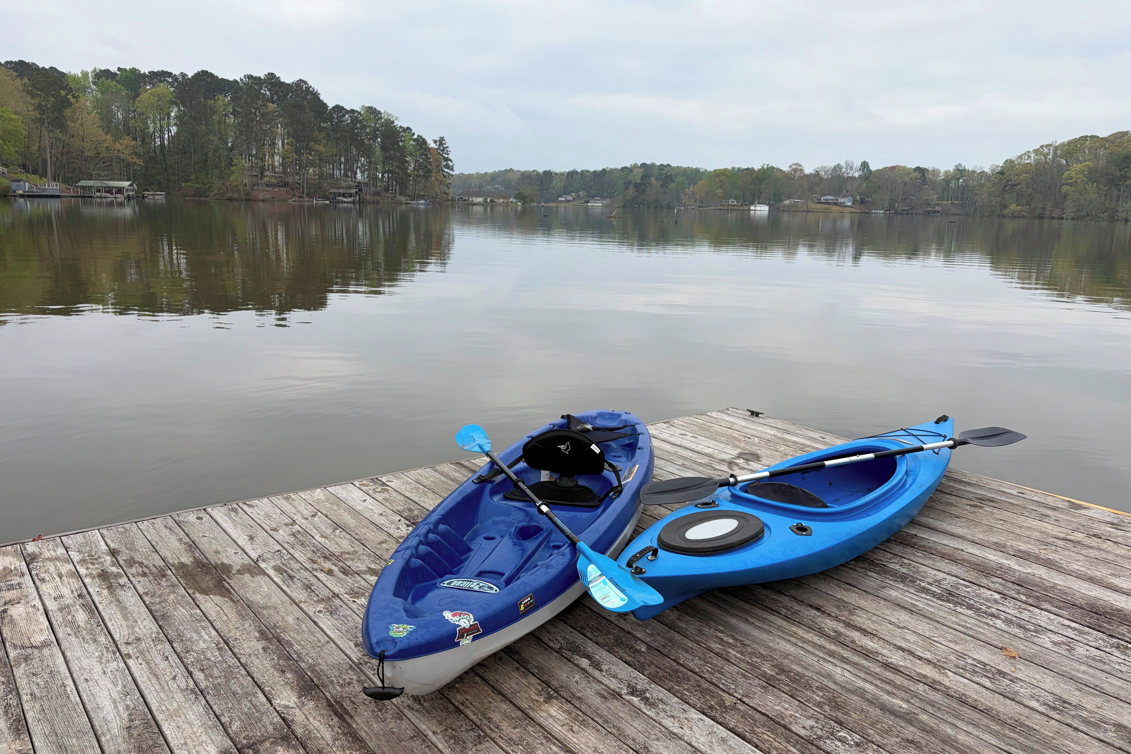 Une jetée en bois avec deux kayaks et une planche à pagaie.