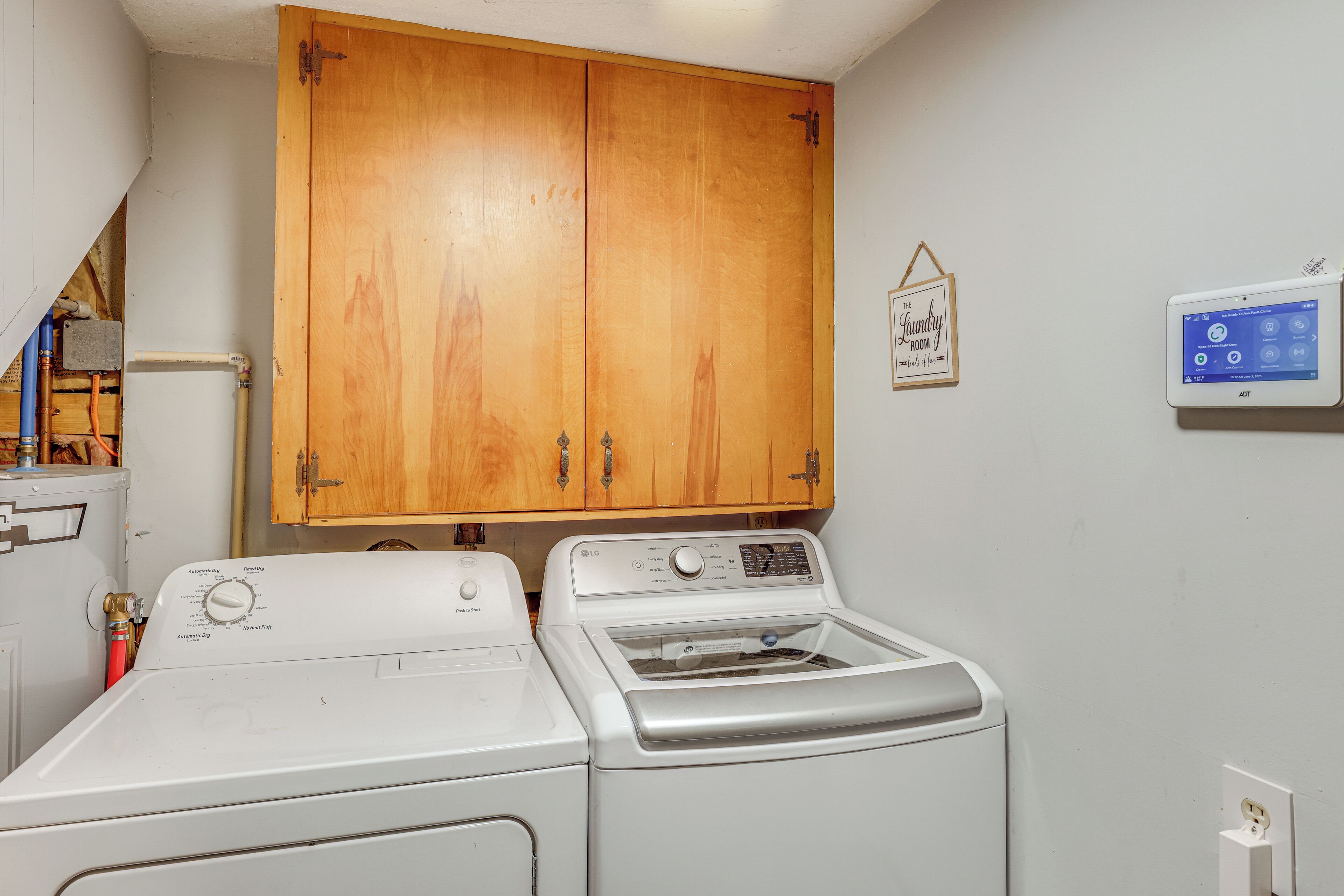 A laundry room with a wooden cabinet and a wall-mounted washing machine.