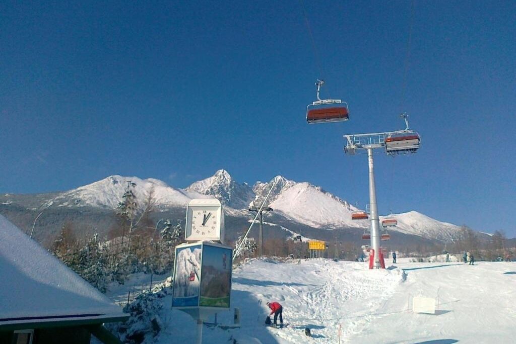 Een skilift met een klok en een berg op de achtergrond.