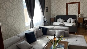 Una habitación de hotel moderna con un sofá grande, una cama con cabecera de madera y un candelabro.