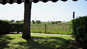 A tree-lined pathway with a grassy area and a fence in the background. - A bright and airy retreat in Bibione (Bibione)