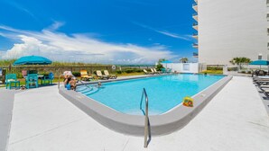 A swimming pool with lounge chairs and umbrellas, surrounded by a high-rise building. - Gulf-view retreat w/ beach access (Panama City Beach)