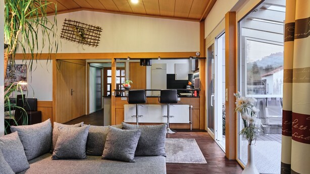 A modern living room with a sofa, a dining area, and a kitchen. - Holiday Home 'Am Millibach' with Private Terrace, Private Garden and Wi-Fi (Wehingen)