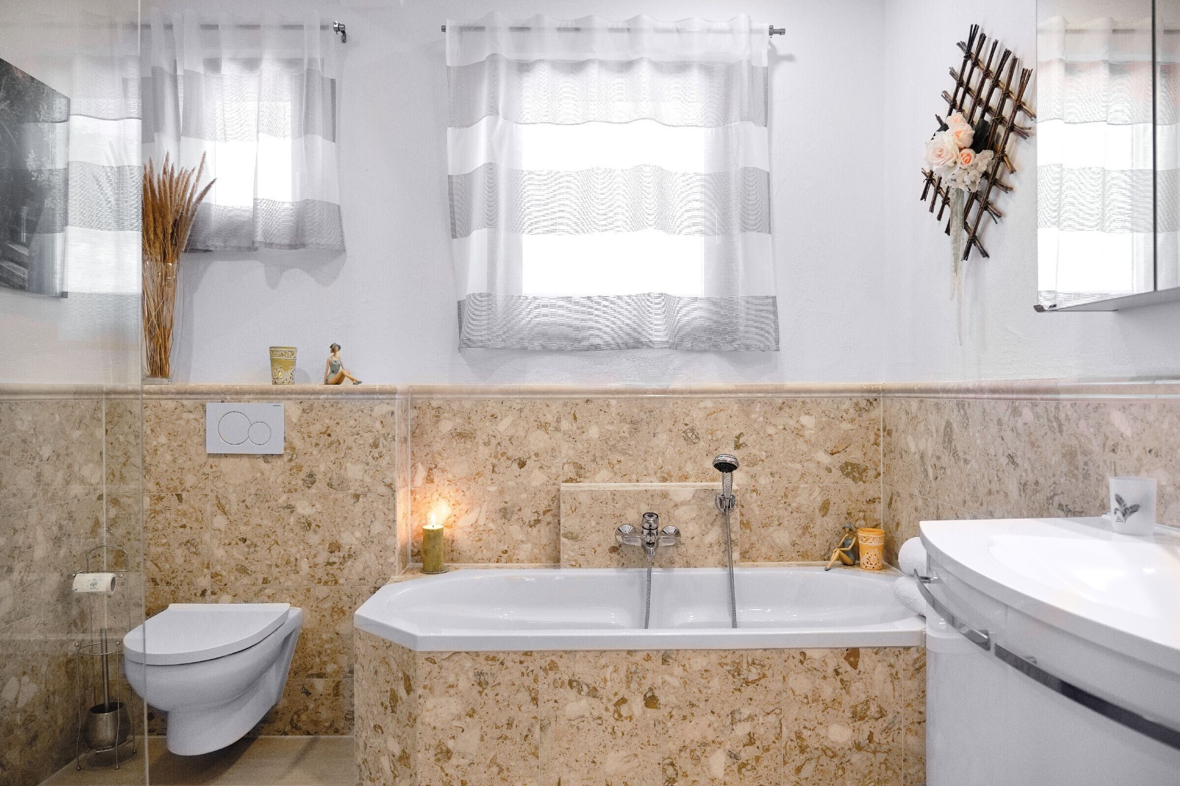Une salle de bain comprenant des toilettes, un bidet et une baignoire, avec des murs en marbre et un élément décoratif mural.