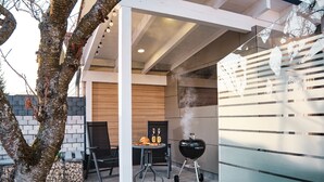 An outdoor patio with a grill, chairs, and a table with food. - Holiday Home 'Am Millibach' with Private Terrace, Private Garden and Wi-Fi (Wehingen)