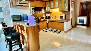 A kitchen with a central island, bar stools, a microwave, a stove, and cabinets. - Len's Staycation 3bdr-2br-downstairs ,netflix&wifi (Davao)