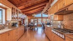 Un'ampia cucina con mobili in legno, un'isola centrale e un'ampia finestra che garantisce luce naturale.
