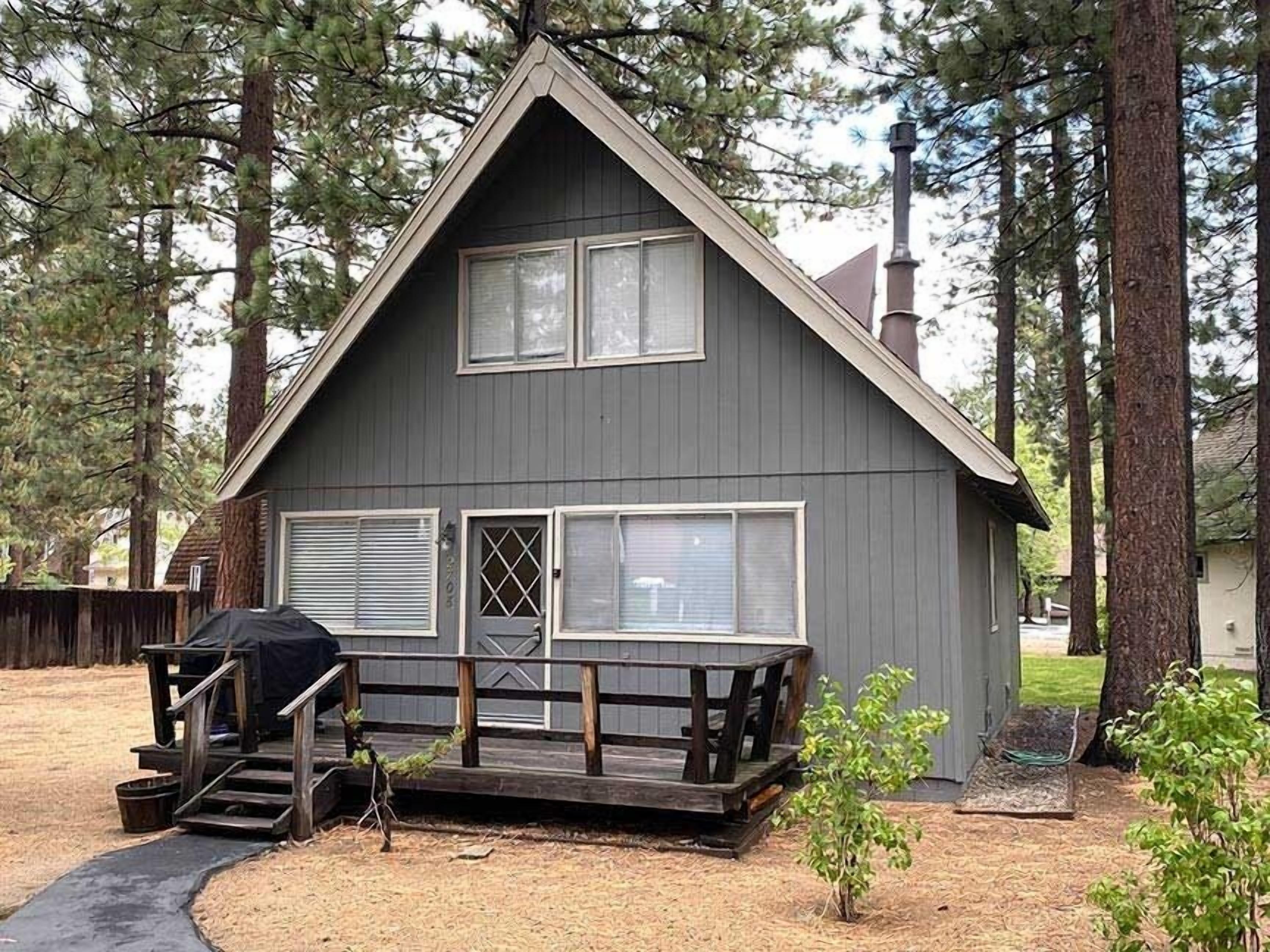 A two-story cabin with a front porch, large windows, and a chimney.