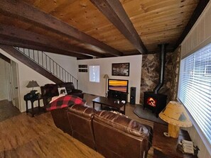 A cozy living room with a fireplace, leather sofa, and a staircase leading upstairs.