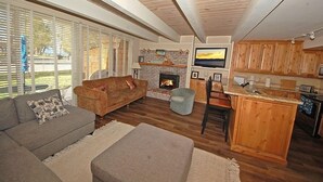 Una sala de estar acogedora con chimenea, comedor y cocina con armarios de madera.