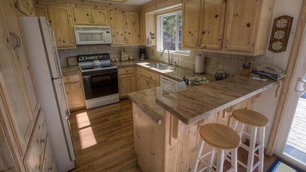 Una cocina con gabinetes de madera, estufa, microondas y ventana.