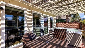 A covered patio area with outdoor furniture, a hot tub, and a view of a mountain landscape. - 2148 Inverness Drive 3 Bedroom Home (South Lake Tahoe)