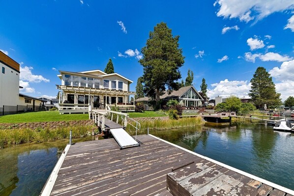 Una propiedad frente al río con muelle, una casa con una amplia terraza y un río tranquilo.