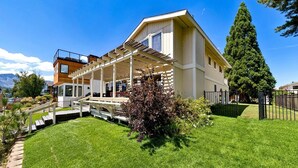 Une maison à deux étages dotée d’un patio couvert et d’une pelouse bien entretenue.