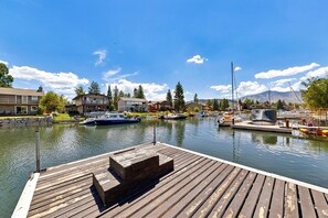 Un puerto deportivo con barcos amarrados, un muelle de madera y edificios residenciales al fondo.