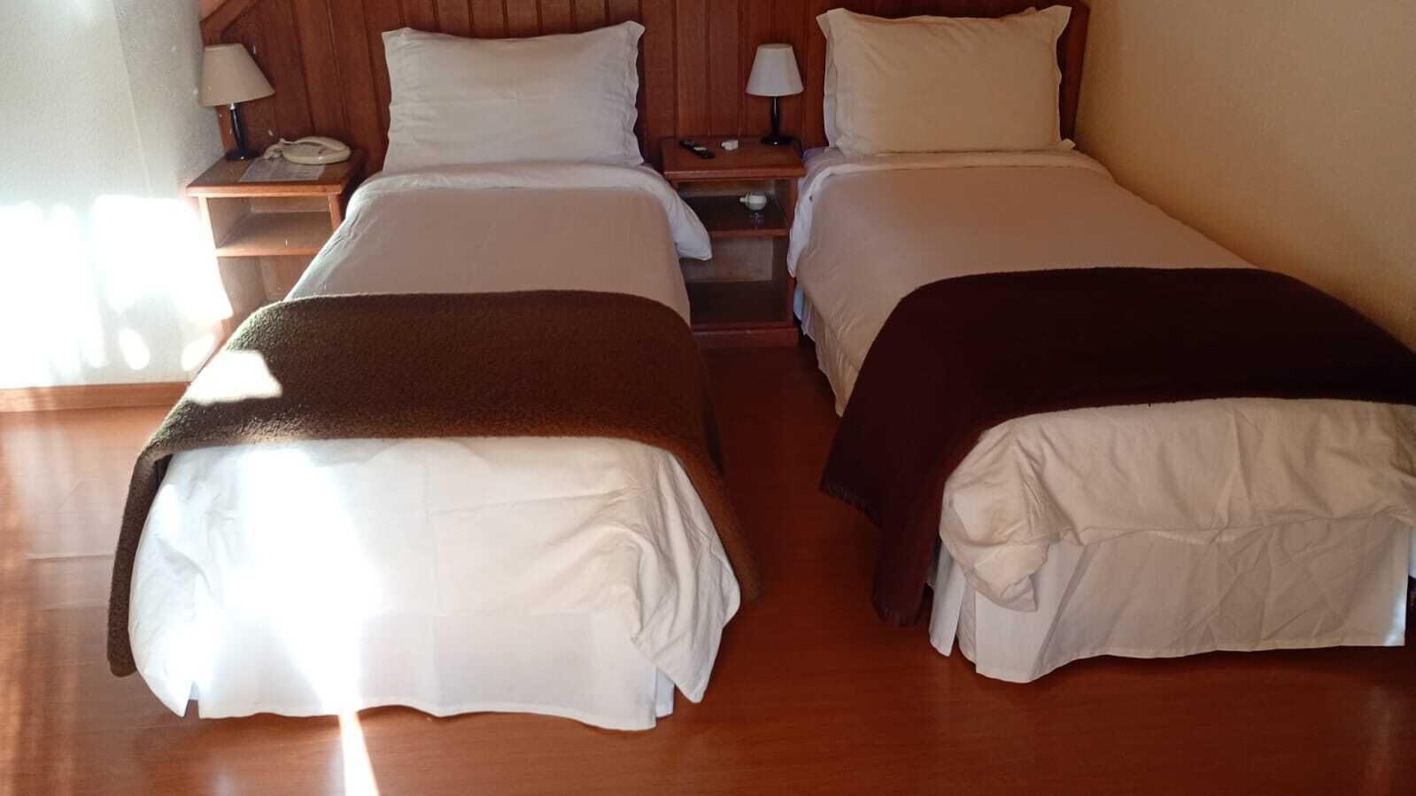 A double bed room with two bedside tables, each with a lamp and a phone.