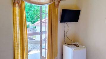 A room with a sliding glass door, a white washing machine, a wall-mounted TV, and a ceiling fan.