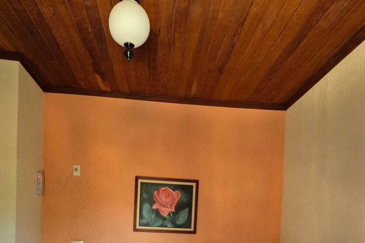 Ein Hotelzimmer mit Holzboden, einem Einzelbett mit weißer Bettwäsche, zwei Nachttischen mit Lampen und einem gerahmten Rosenbild an der Wand.