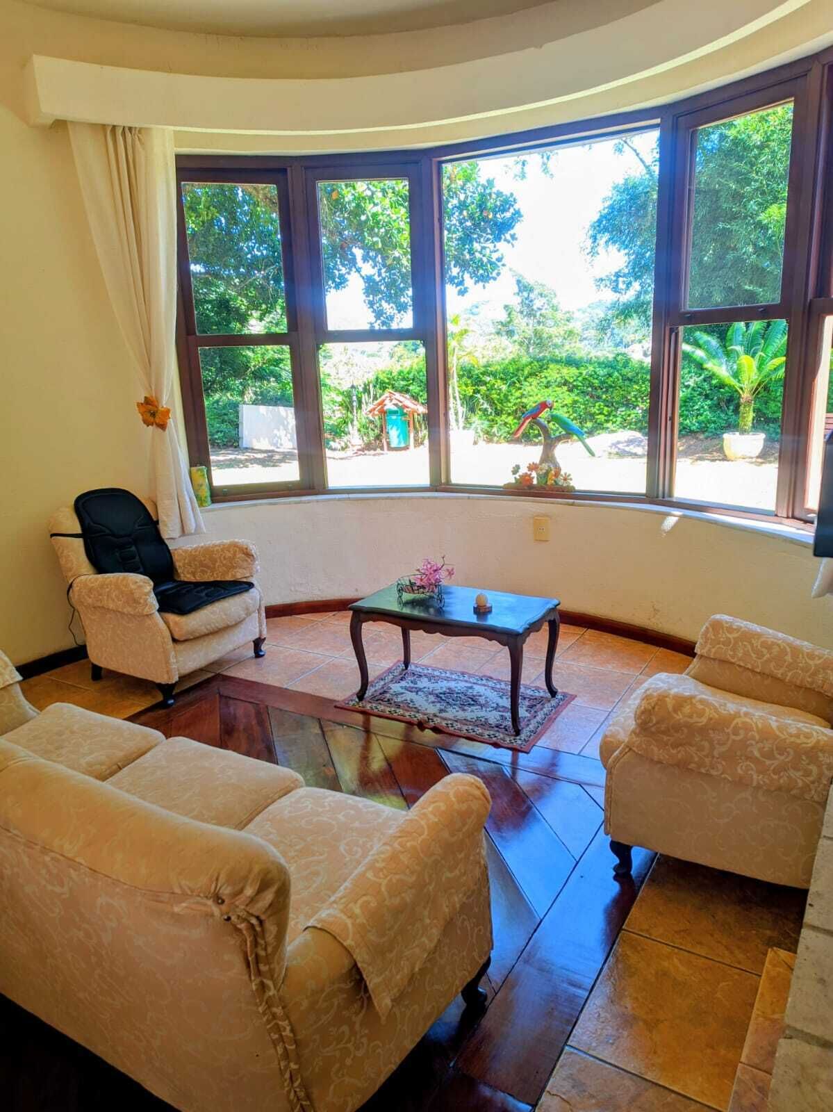 A room with a curved window, two sofas, a small table, and a chair.