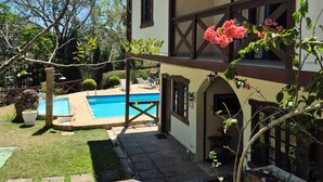 Une maison à deux étages avec une piscine, un balcon et un jardin.