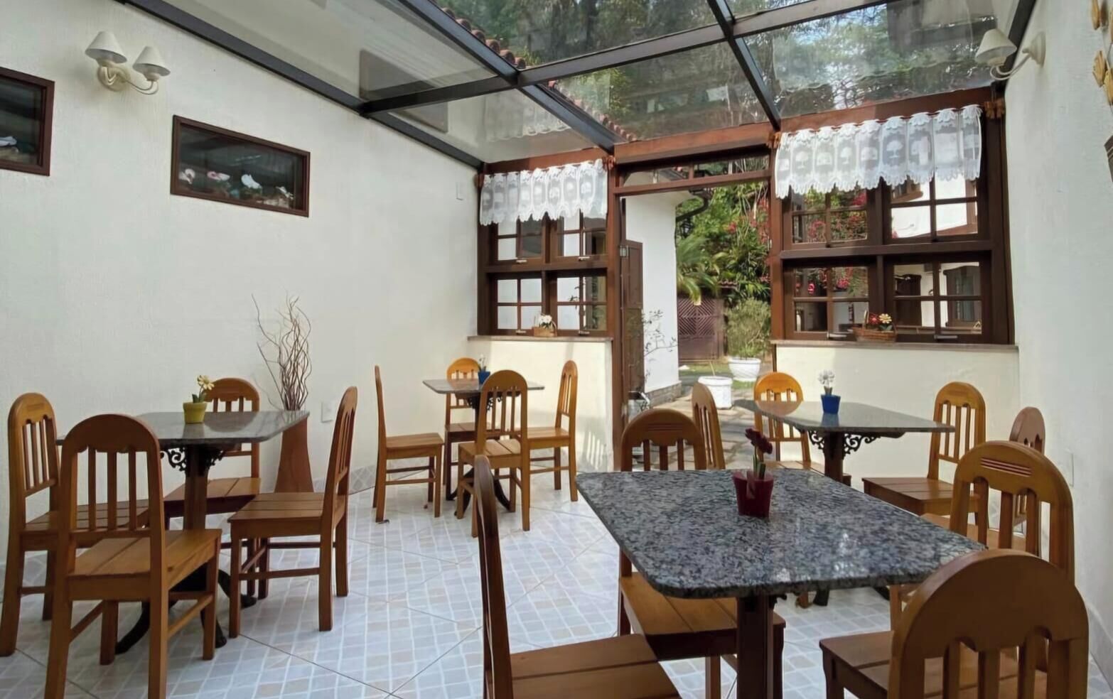 Un comedor con mesas y sillas de madera, techo de cristal y vistas al exterior.