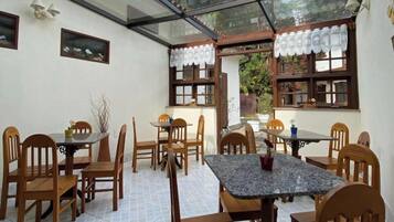 Un comedor con mesas y sillas de madera, techo de cristal y vistas al exterior.