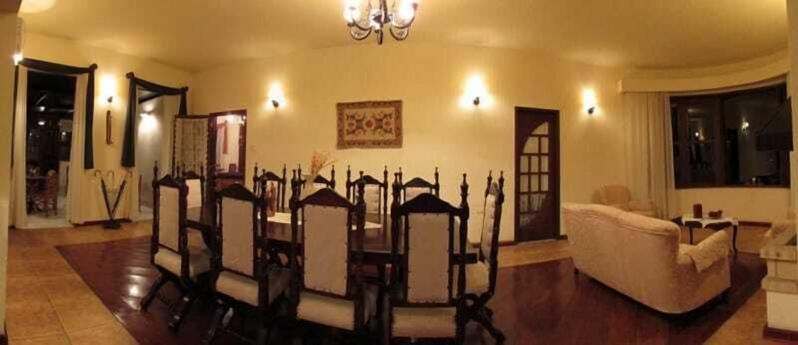 Uma sala de jantar com mesa redonda e cadeiras, um sofá e um candelabro.