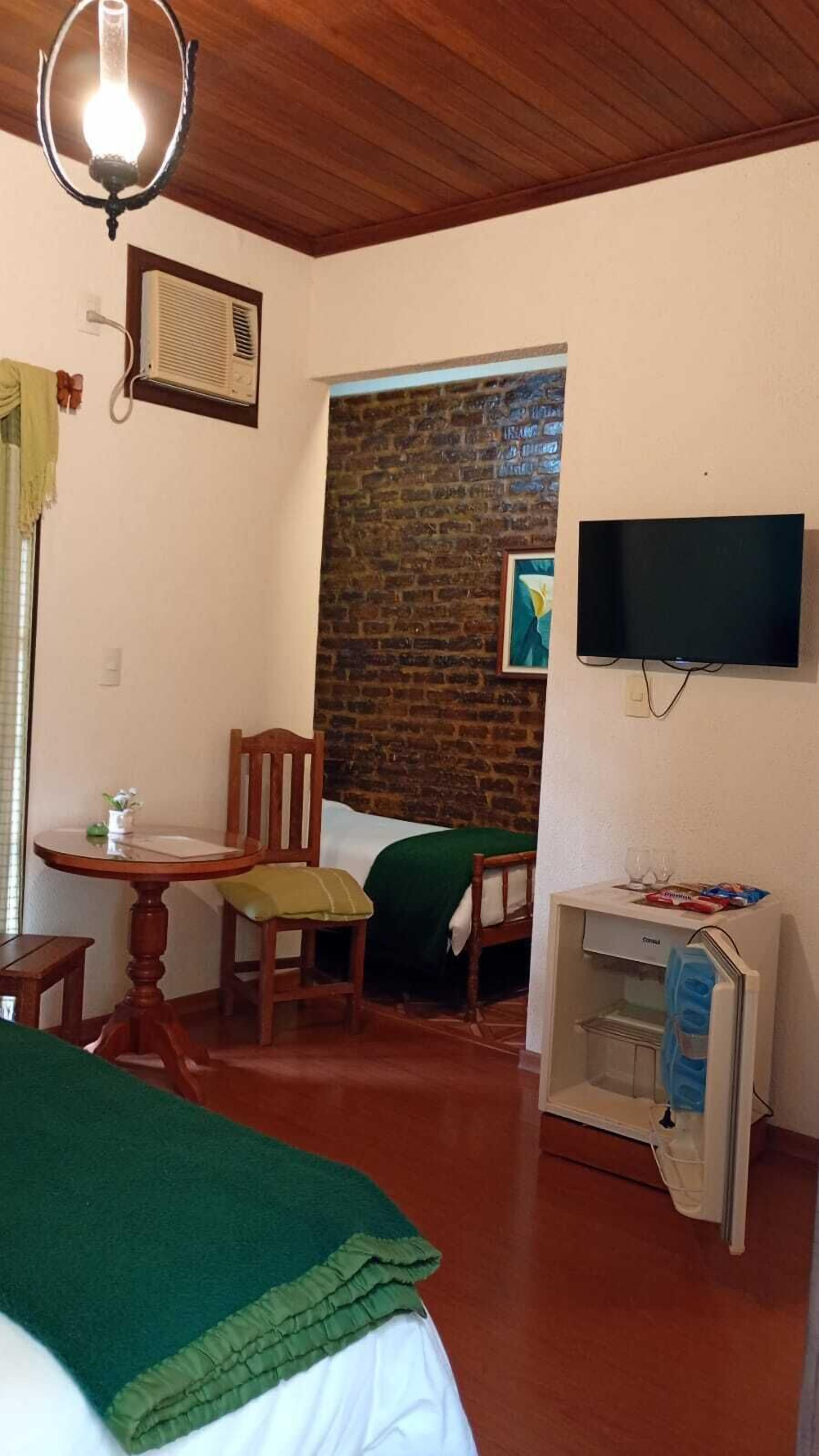 Une chambre comprenant un lit, un bureau, une chaise, une télévision et un réfrigérateur.
