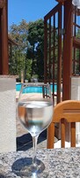 Un vaso de agua sobre una mesa, con una piscina al fondo.