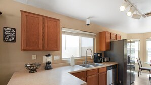 A kitchen with wooden cabinets, a stainless steel refrigerator, a dishwasher, and a coffee maker. - 3 Bedrooms Near State Farm Stadium Pets (Phoenix)