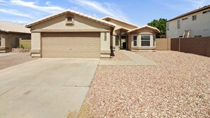 A residential house with a garage, a driveway, and a gravel lawn. - 3 Bedrooms Near State Farm Stadium Pets (Phoenix)