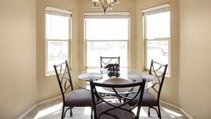 A dining area with a round glass table, four chairs, and a chandelier. - 3 Bedrooms Near State Farm Stadium Pets (Phoenix)