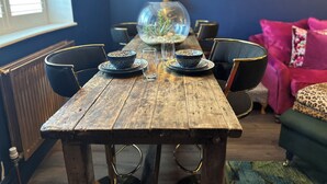 Een rustieke houten eettafel met twee stoelen, een glazen schaal en een glas.