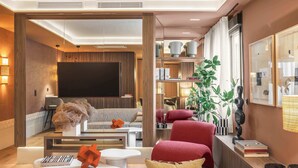Una sala de estar moderna con una televisión de pantalla plana, asientos cómodos, una mesa de centro y una estantería.