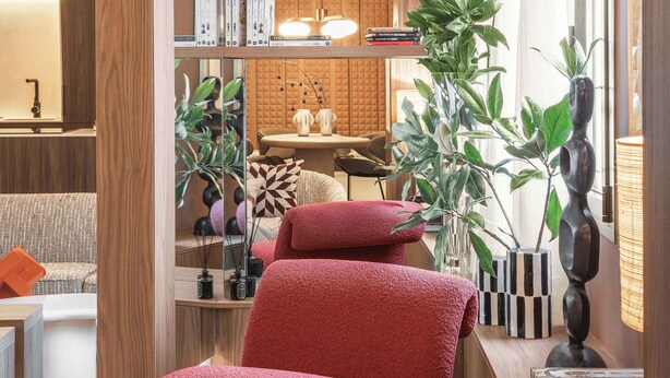 Un interior moderno con un sofá, poufs rojos, una planta y una estantería.