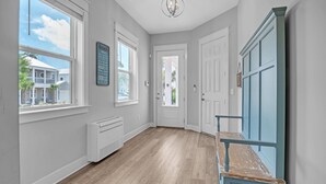 A hallway with hardwood floors, white walls, and a blue door.