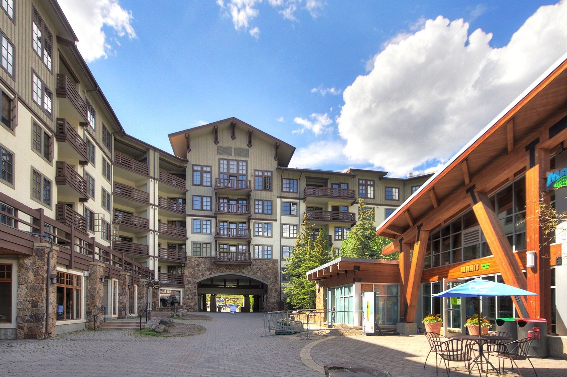 A multi-story building with balconies, a stone facade, and a covered entrance.