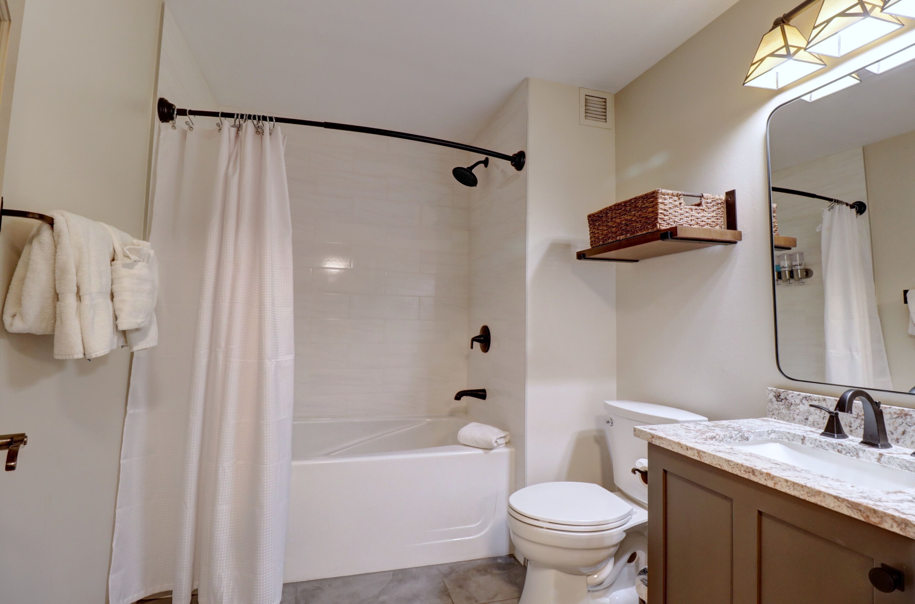 A modern bathroom with a bathtub, toilet, and vanity.