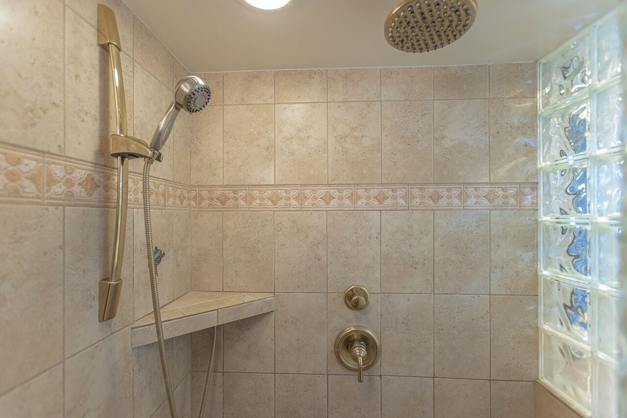 A shower with a handheld showerhead and a wall-mounted faucet.