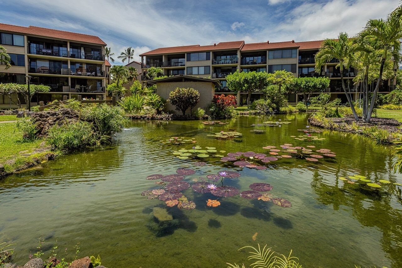 Un hôtel doté d’un étang, entouré de verdure et surplombant un ciel dégagé.