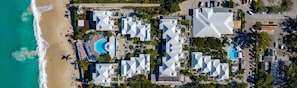 Una vista aerea di un resort con diversi edifici, una spiaggia e una piscina.