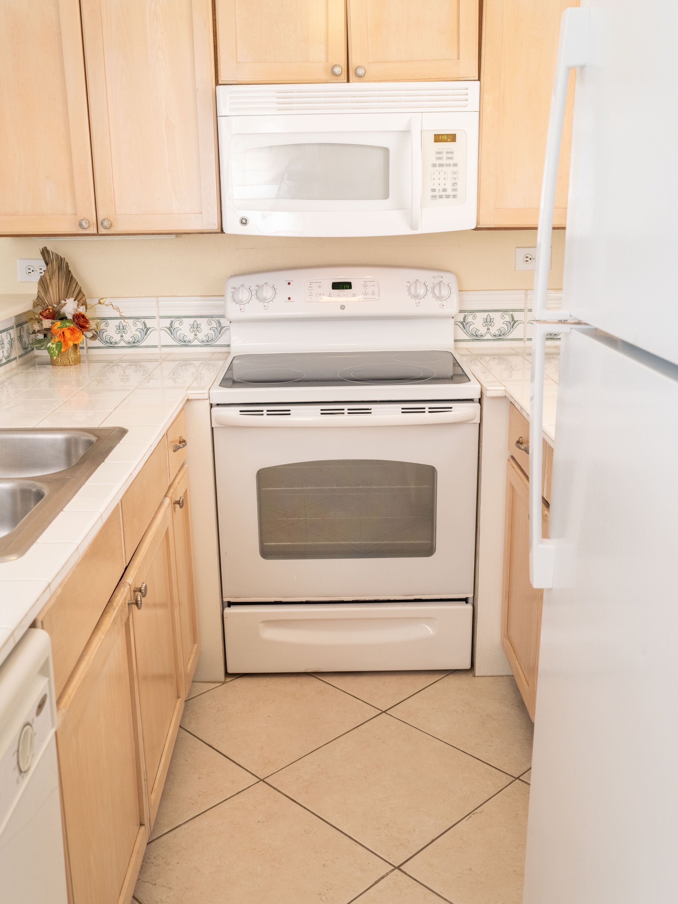 A compact kitchen with wooden cabinets, a built-in microwave, a stove, and a refrigerator.