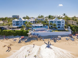 A beachfront hotel with multiple buildings, a pool area, and beach chairs. - Paradise Island Beach Club (Paradise Island)
