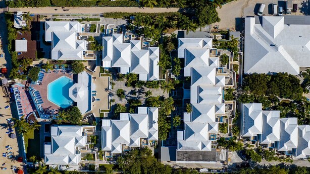 Vue aérienne d’un complexe hôtelier comprenant plusieurs bâtiments, une plage et une piscine.