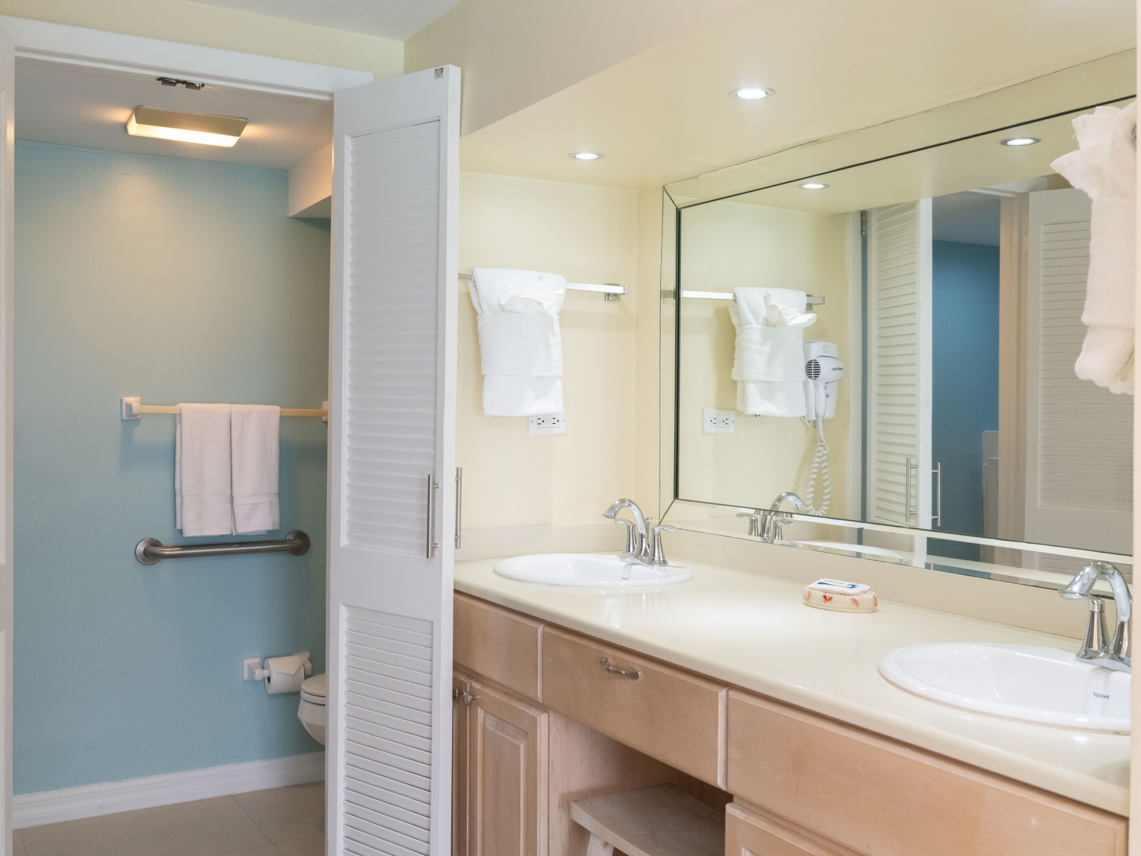 A bathroom with two sinks, a large mirror, and a towel rack.
