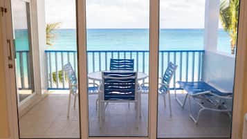 A balcony with a table and chairs, a view of the ocean, and a palm tree.