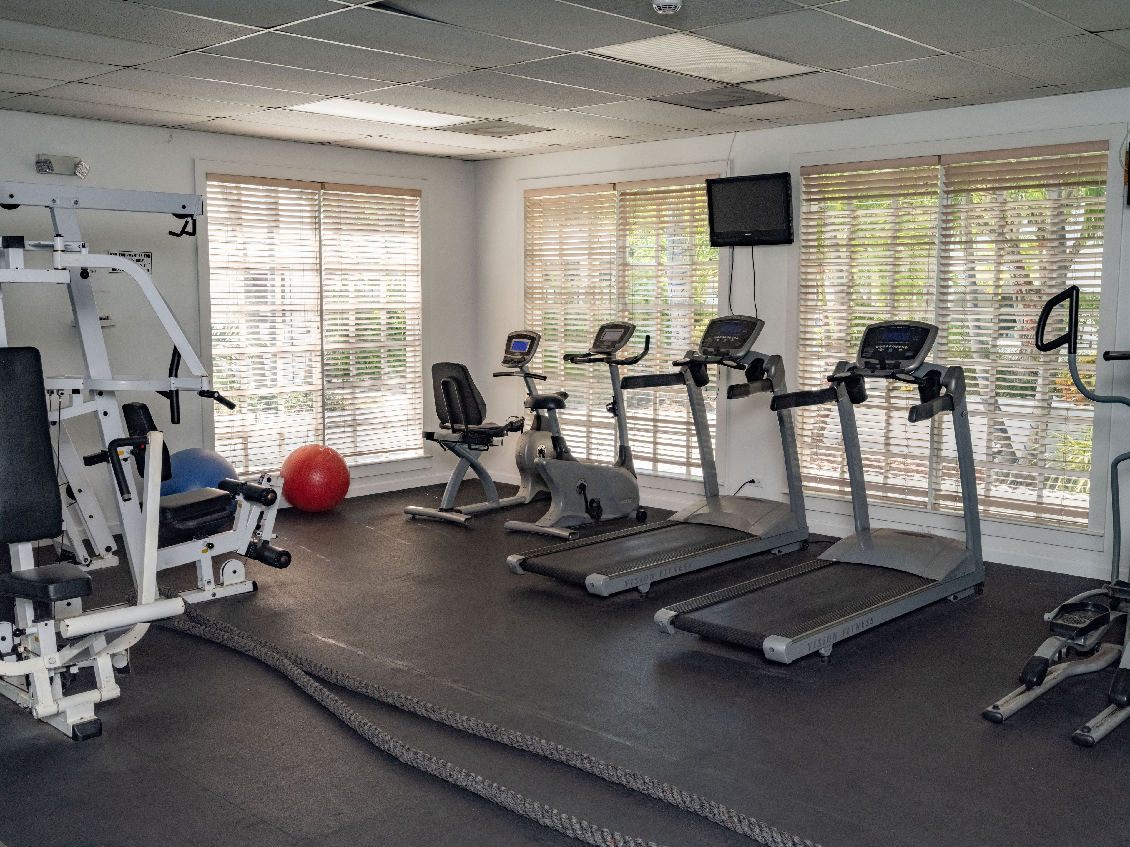 A gym with treadmills, elliptical machines, and a weight bench.