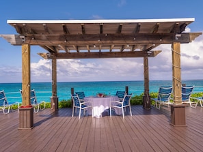 A wooden deck with a pergola, overlooking a turquoise sea. - Paradise Island Beach Club (Paradise Island)
