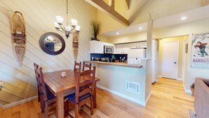 A dining area with a wooden table and chairs, a chandelier, and wall-mounted decorative items.