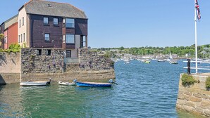A coastal building with a stone wall and a flagpole.